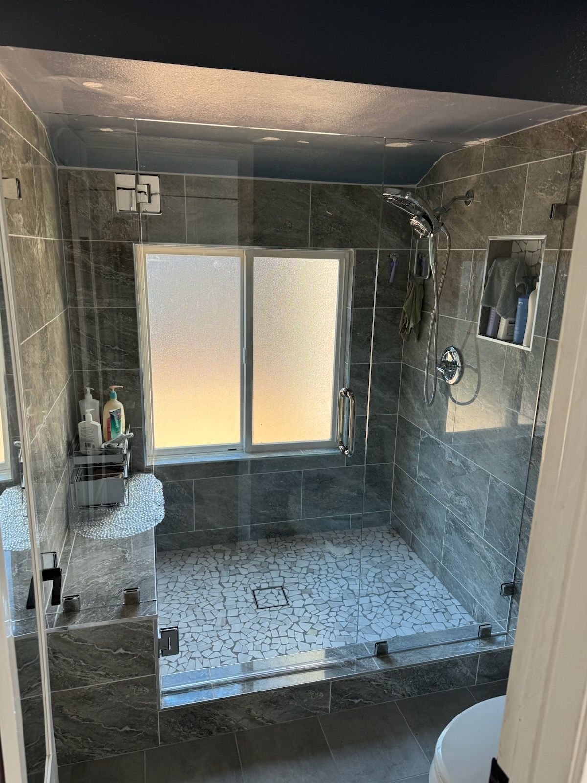 A bathroom with a walk in shower and a window.