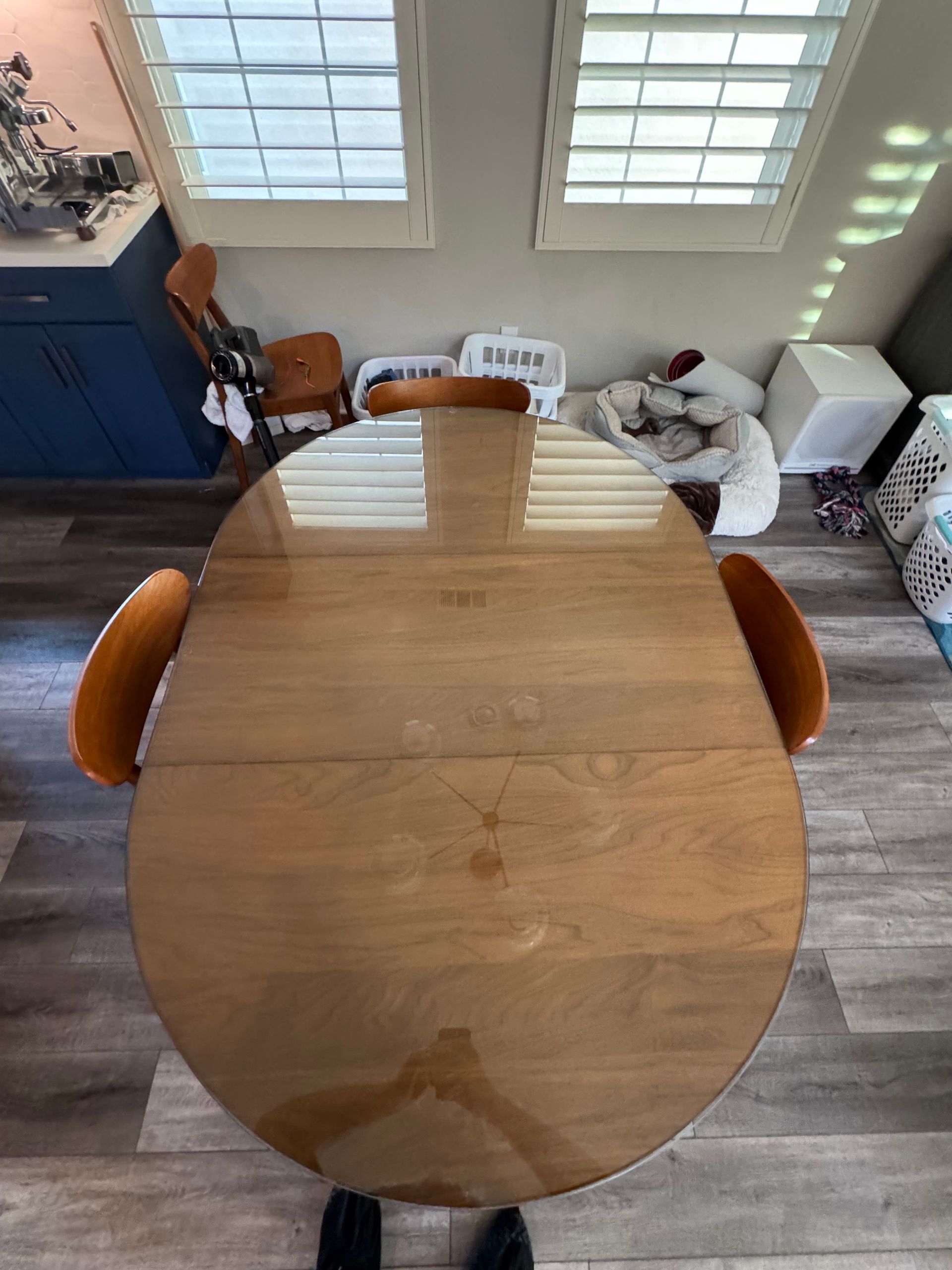 An aerial view of a wooden dining table and chairs in a kitchen.