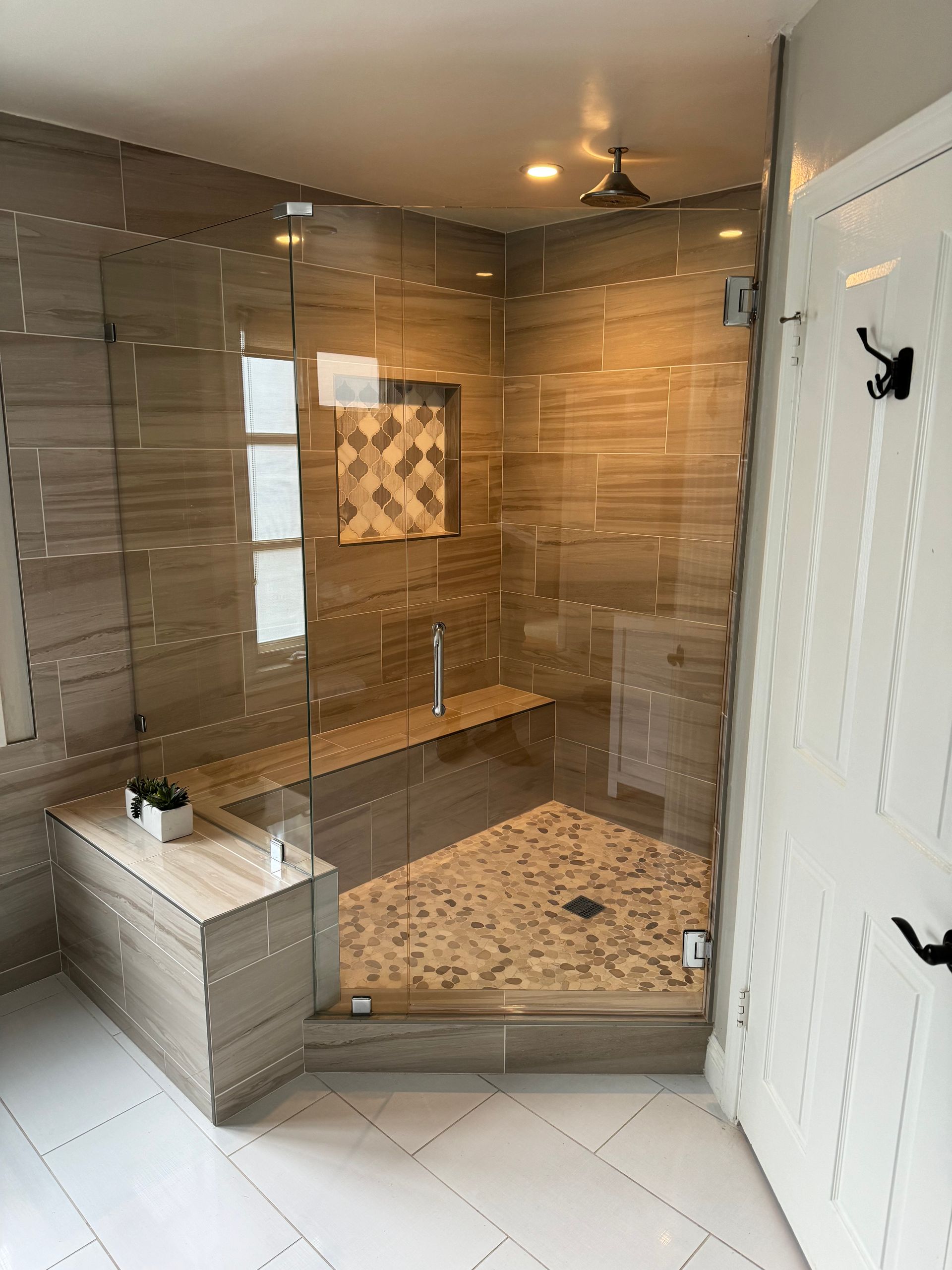 A bathroom with a walk in shower and a bench.