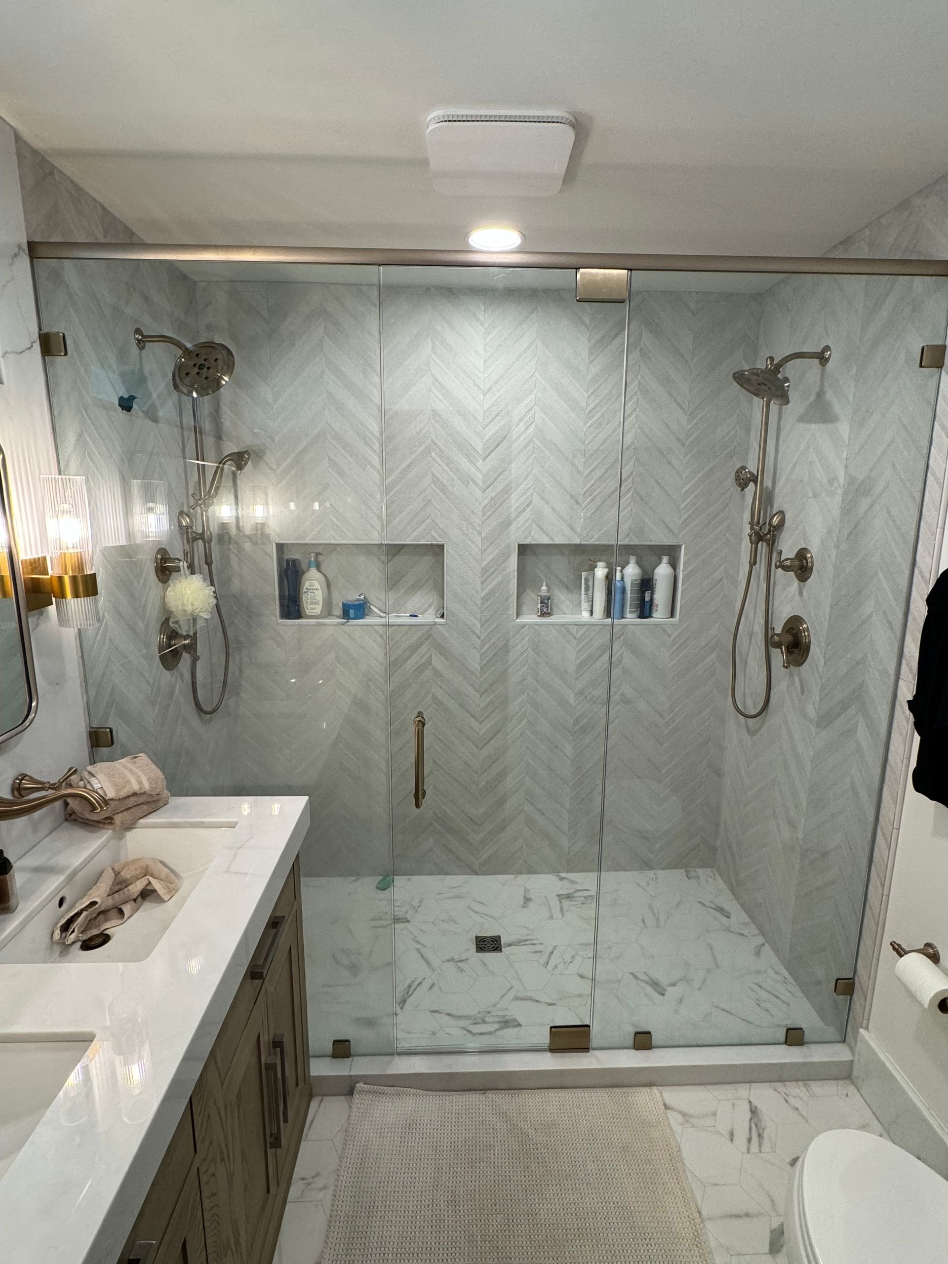 A bathroom with a walk in shower , sink , toilet and mirror.