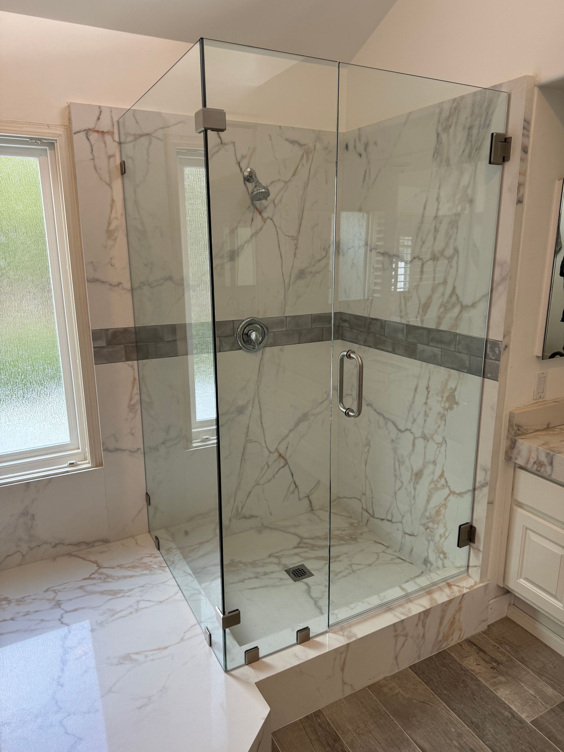 A bathroom with a walk in shower with a glass door.