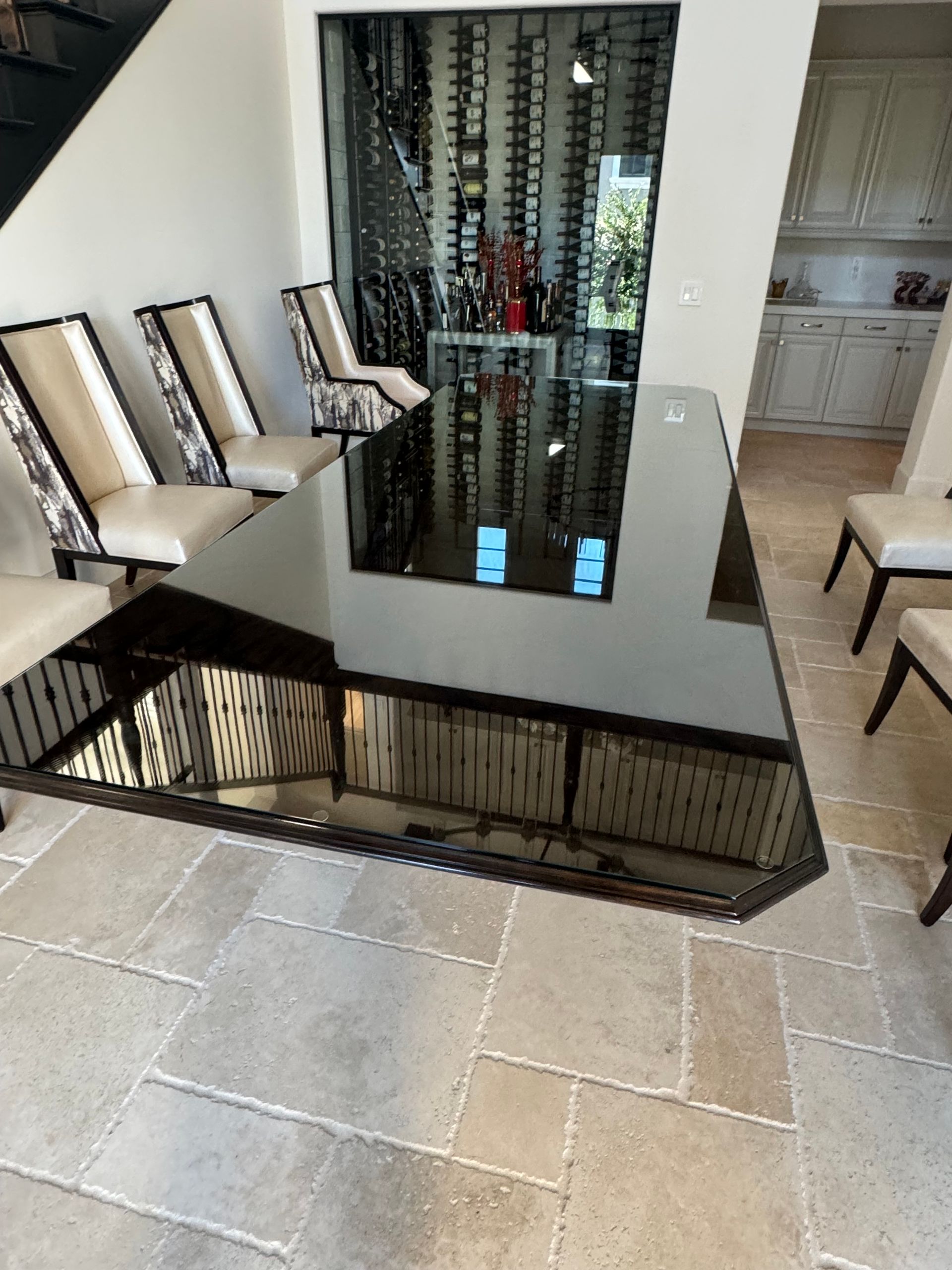 A dining room with a table and chairs and a wine cellar in the background
