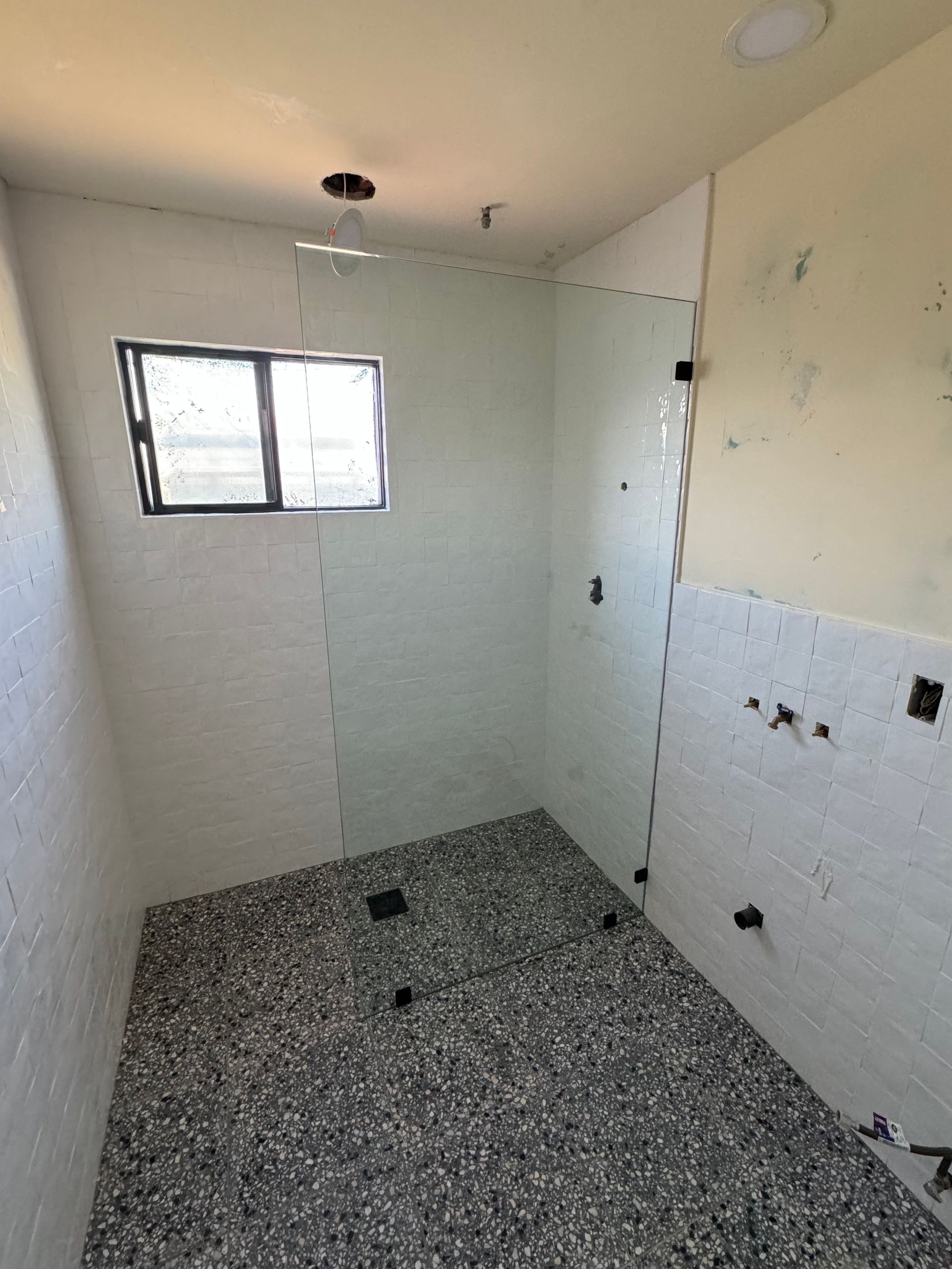 A bathroom with white tiles and a window.