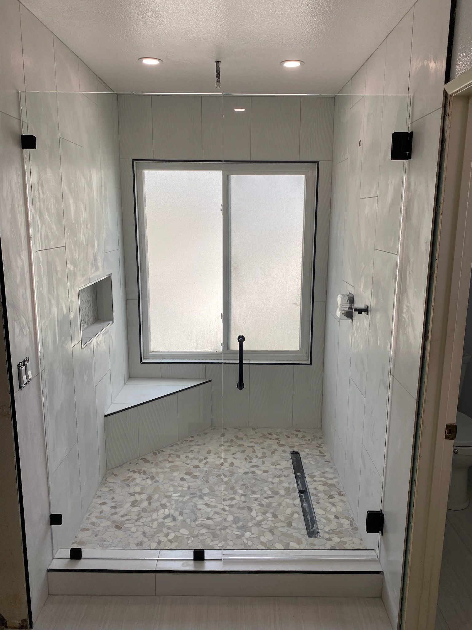 A bathroom with a walk in shower and a window.