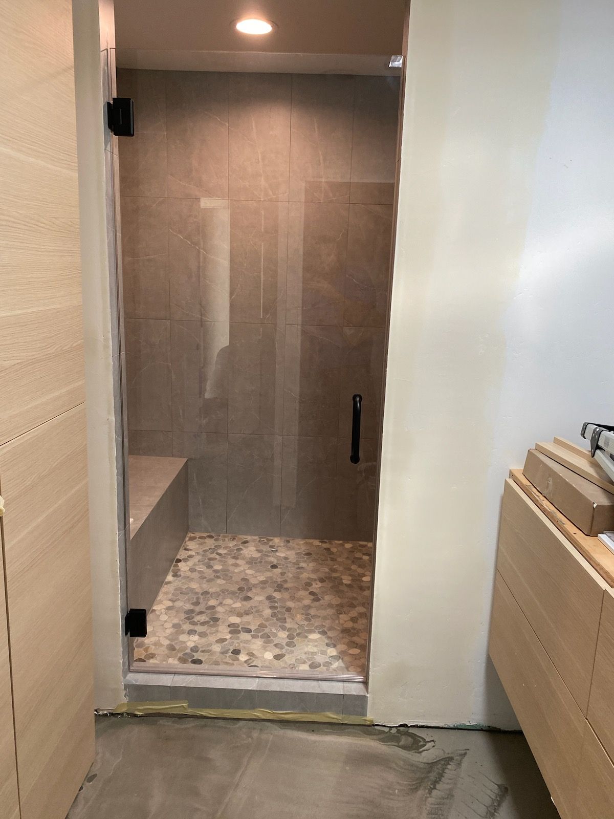 A bathroom with a walk in shower with a glass door.