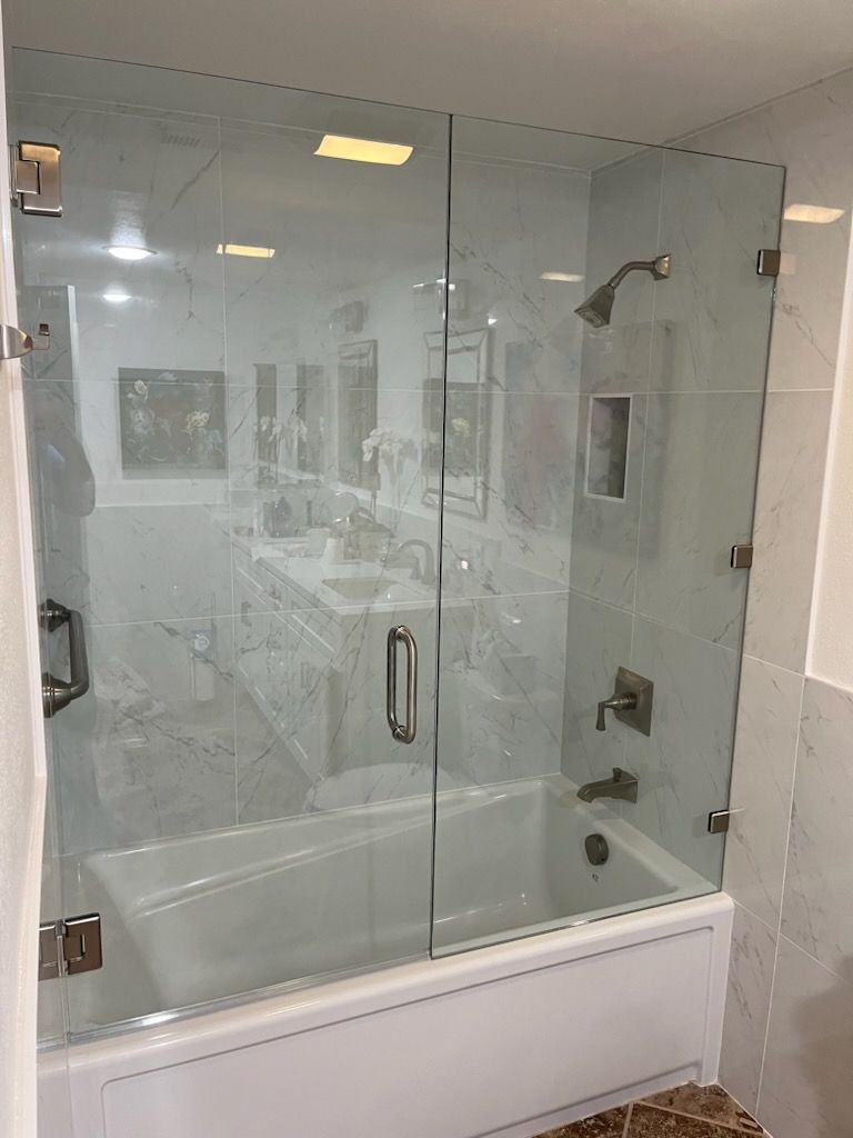 There is a bathtub in the bathroom with a glass shower door.