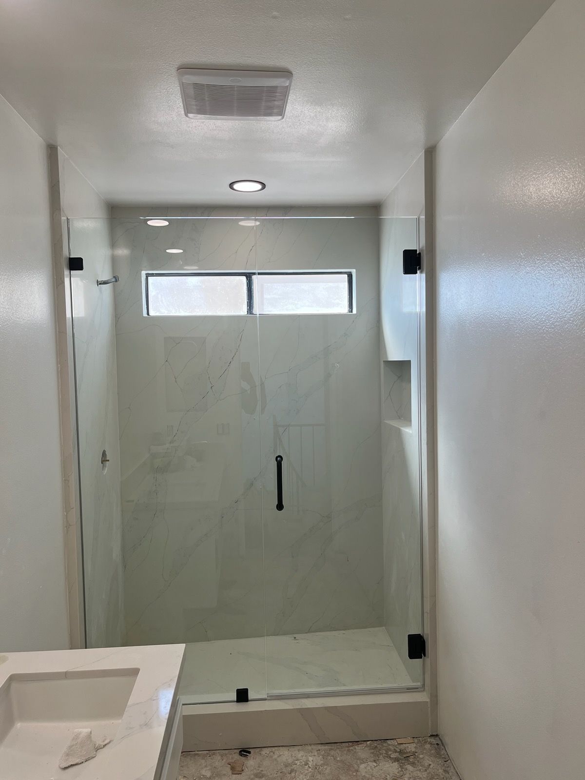 A bathroom with a walk in shower and a sink.