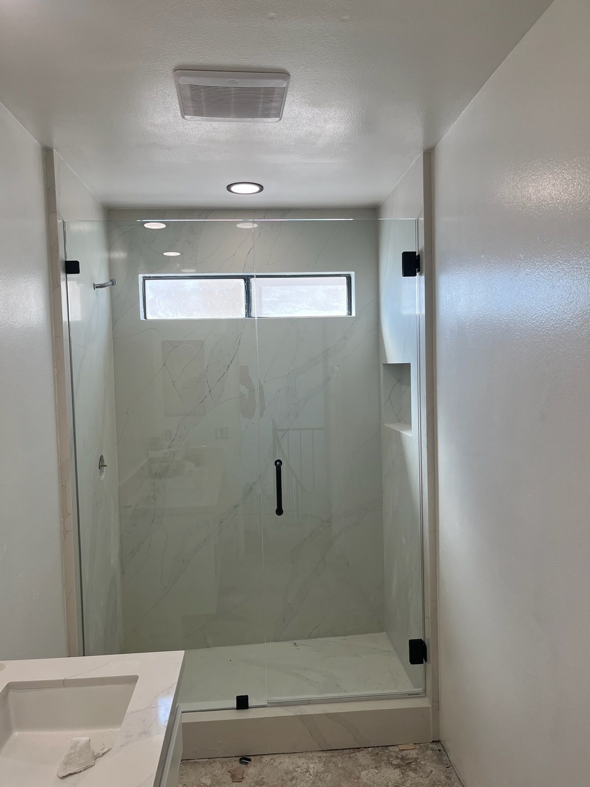 A bathroom with a walk in shower and a sink.