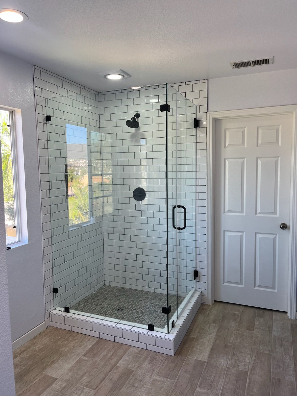 A bathroom with a walk in shower with a glass door.
