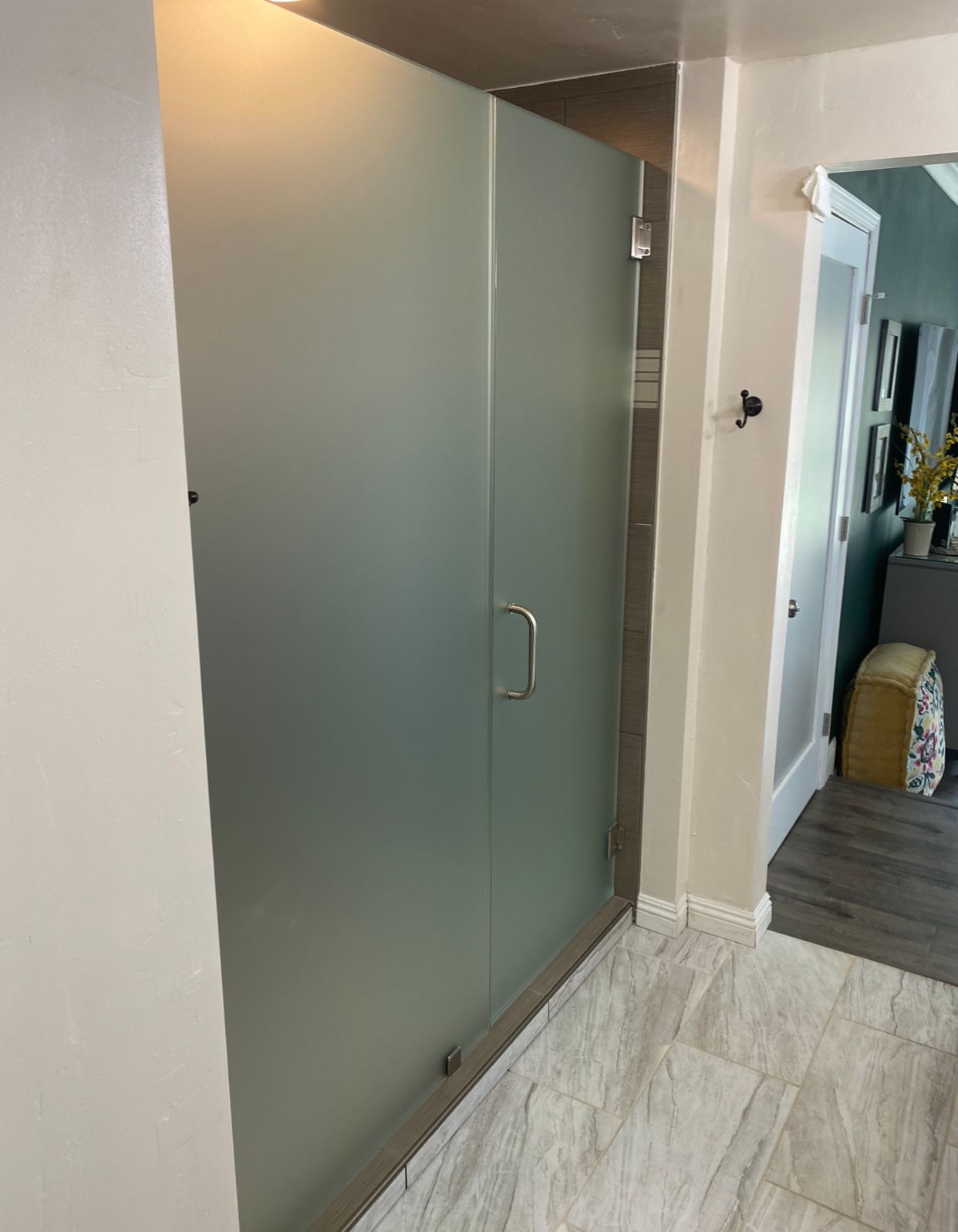 A walk in shower with a frosted glass door in a bathroom.