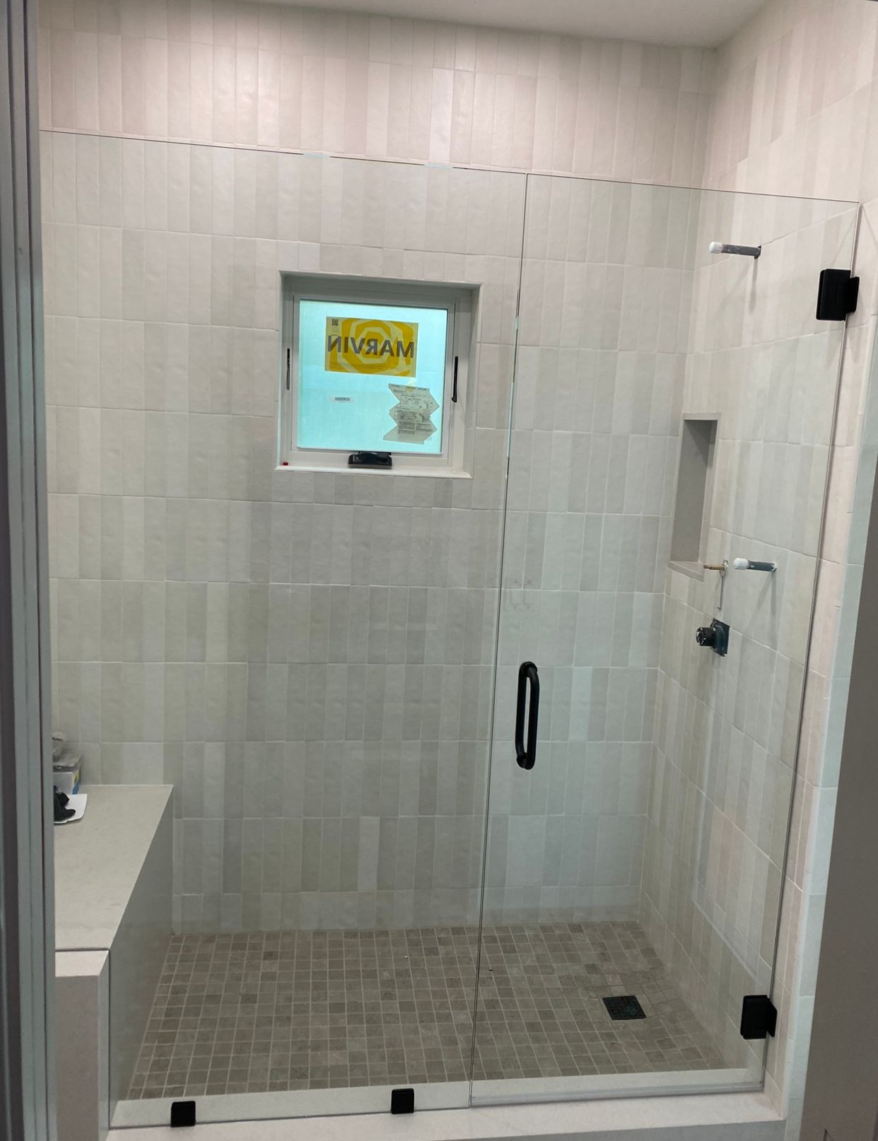 A shower with a glass door and a window