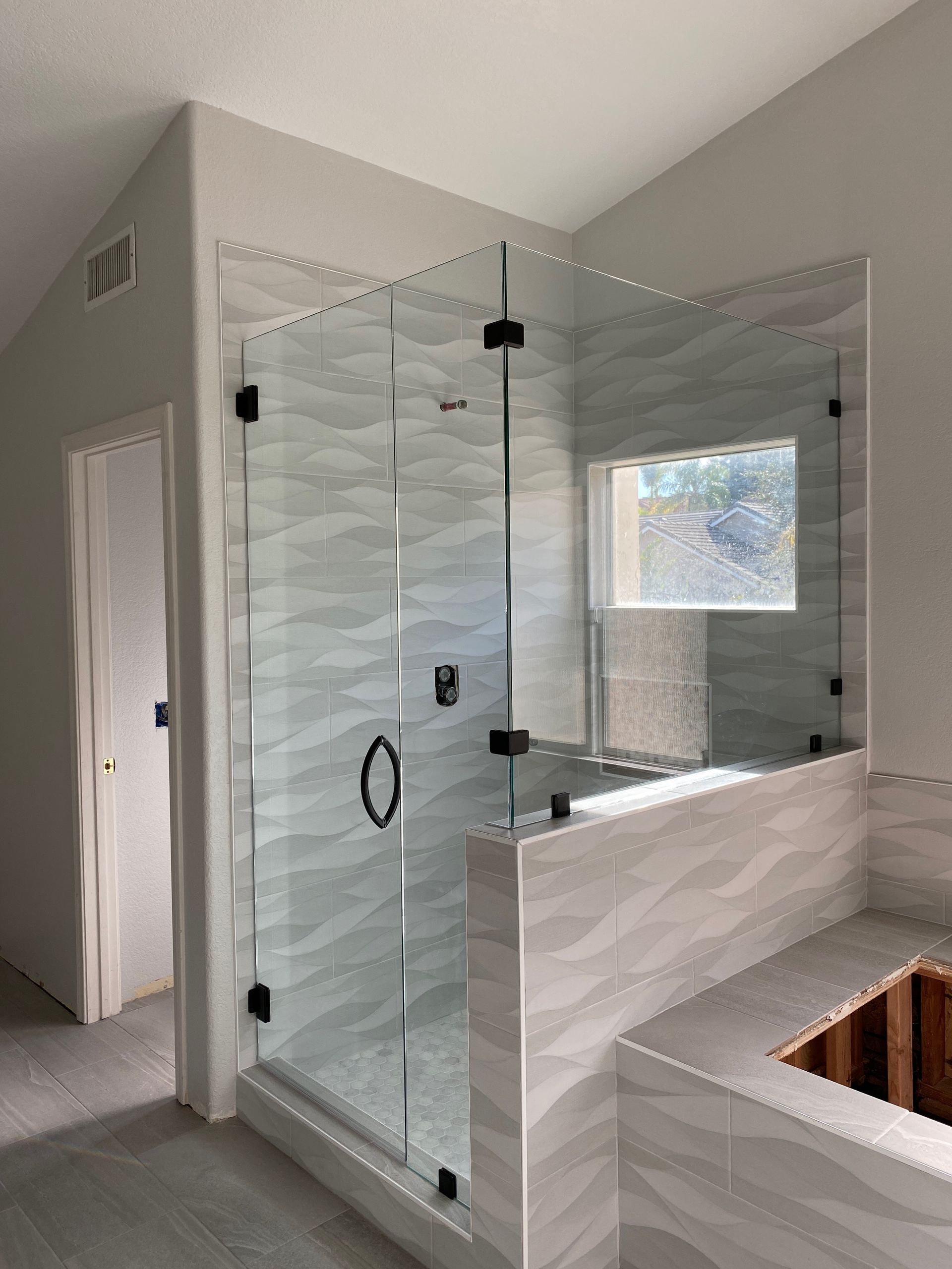 A bathroom with a glass shower door and a window.