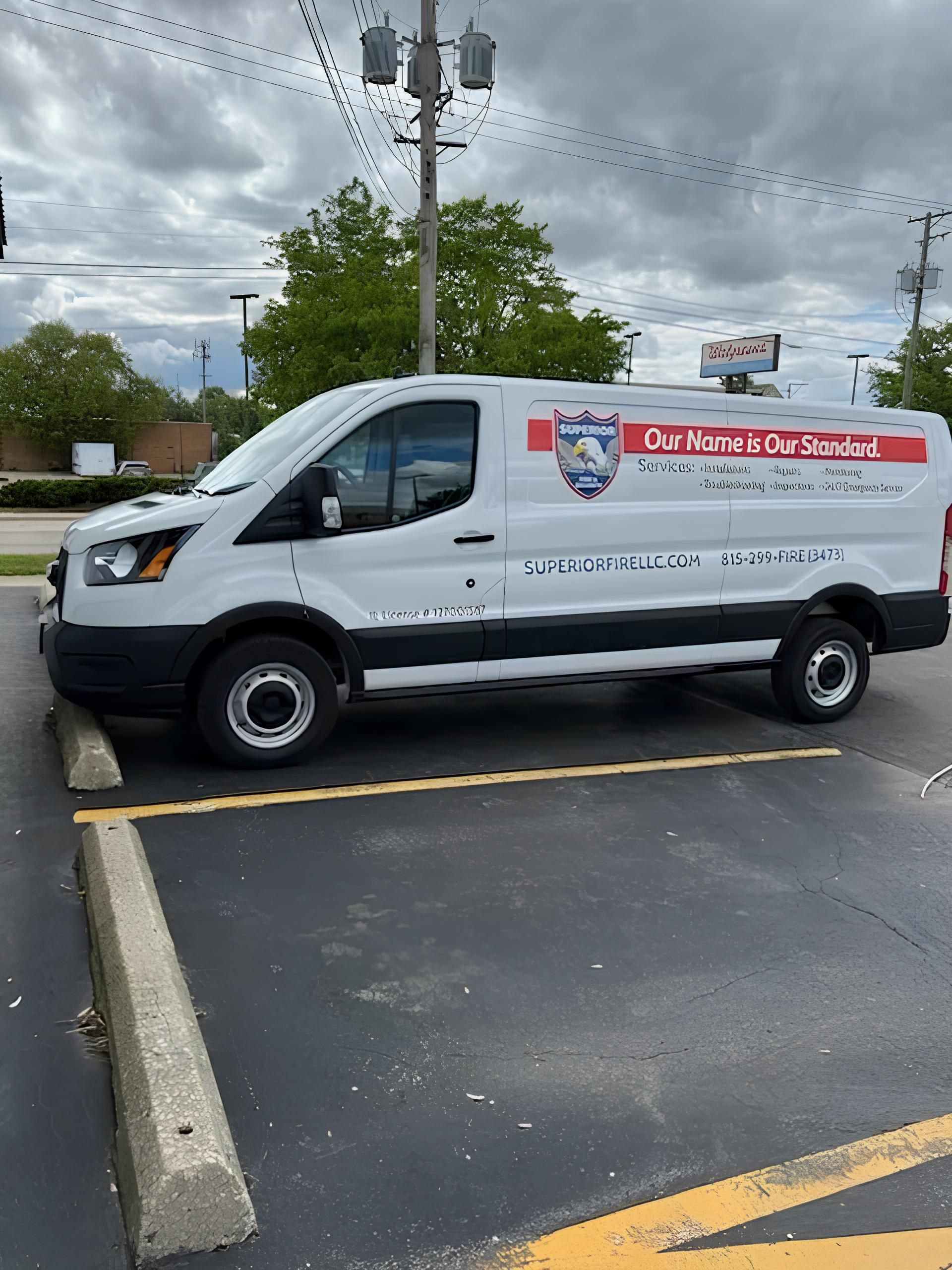 White service van with red logo parked in a lot under cloudy skies.