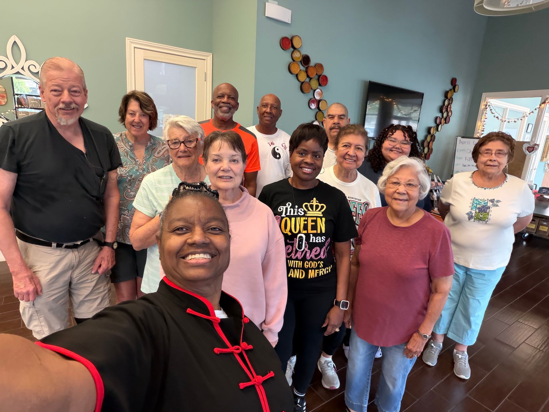 Group of smiling people gathered indoors for a selfie in a living room.