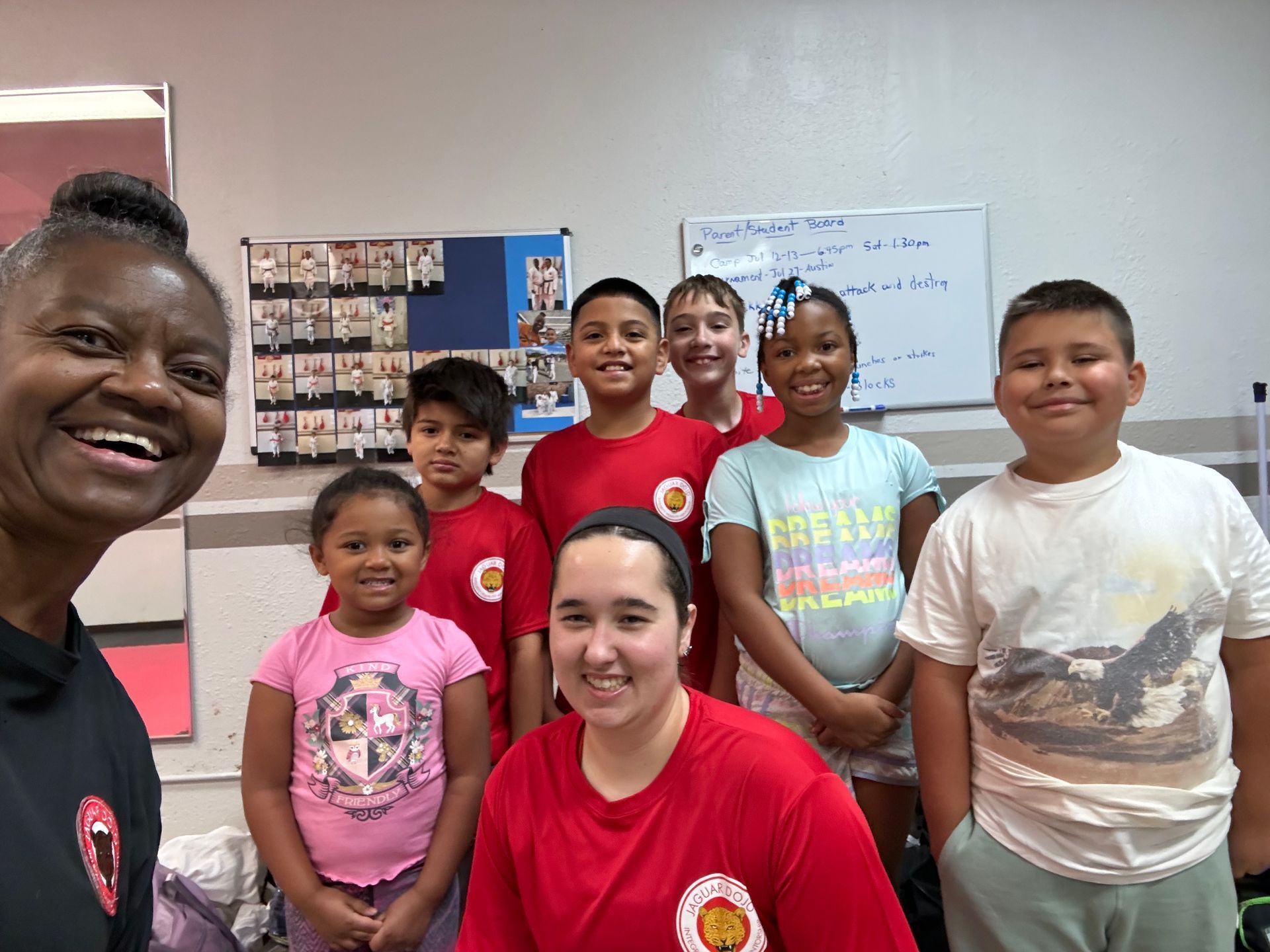 Group of smiling students and two adults posing in a classroom.