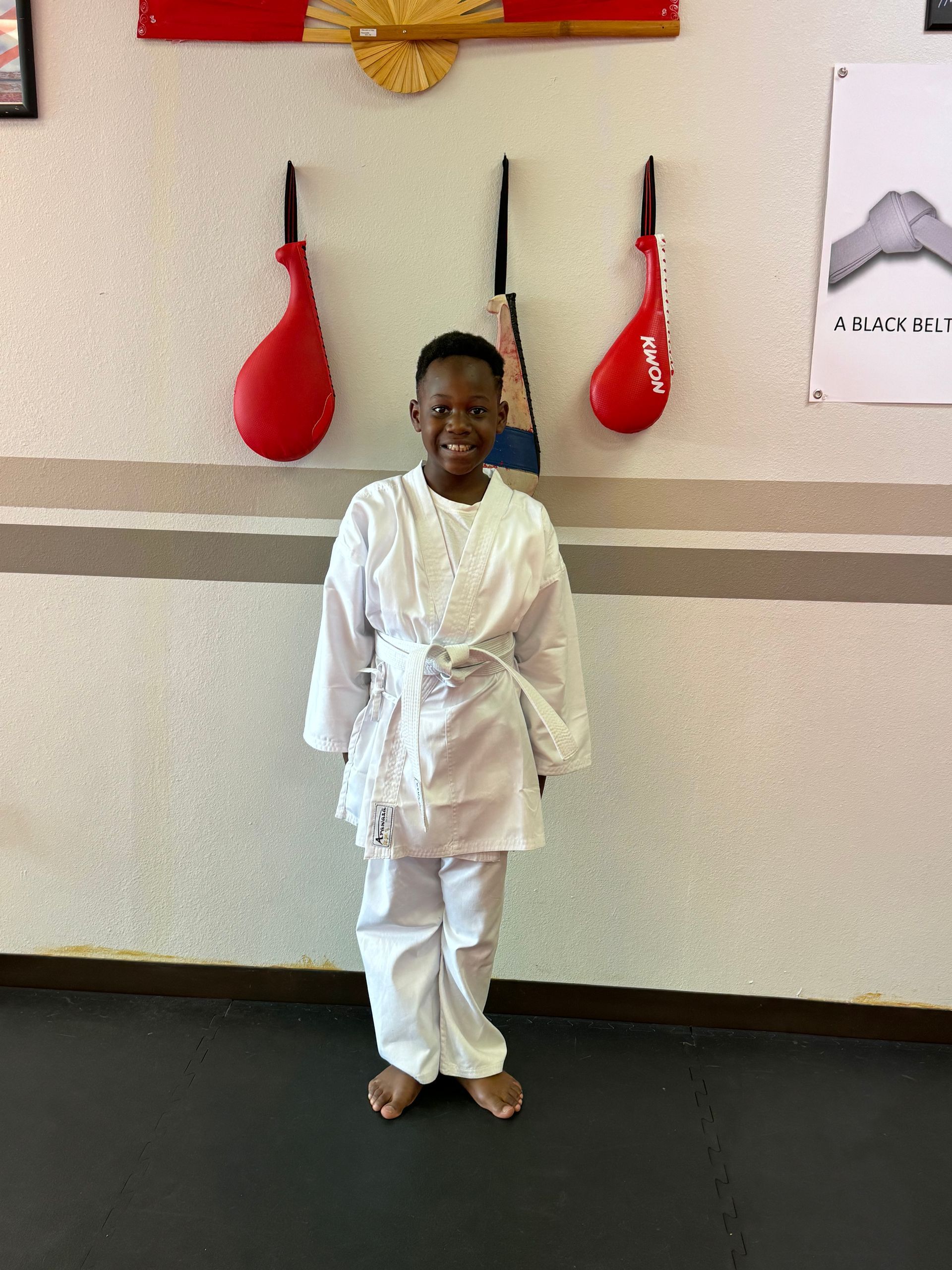 Person in a white martial arts uniform standing in front of red hanging targets on a wall.
