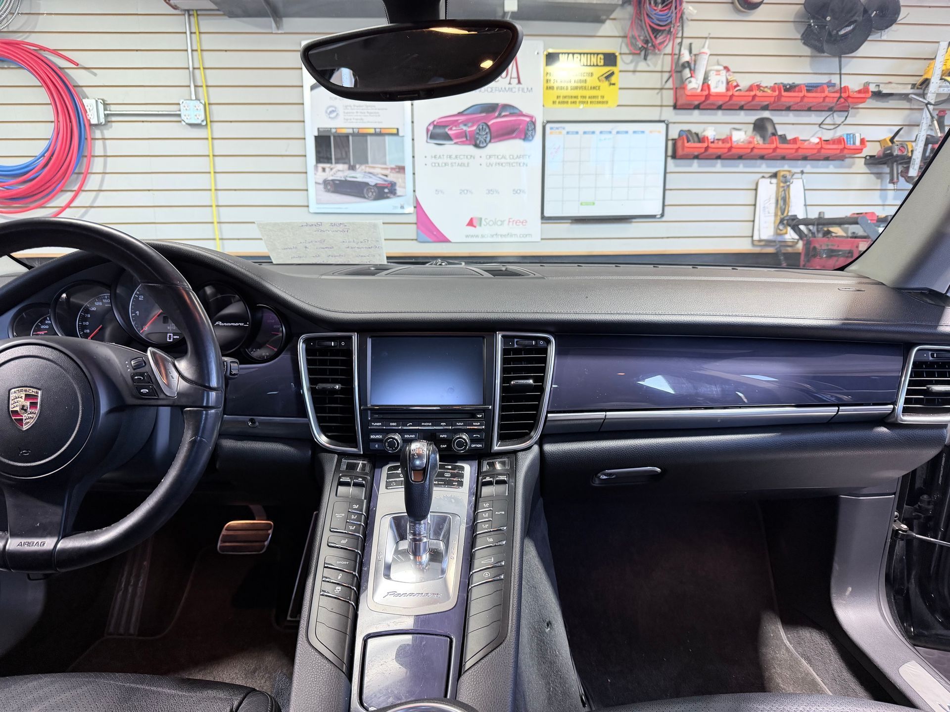 Driver's seat view of a Porsche Panamera interior with a leather dashboard, center console screen, and steering wheel.