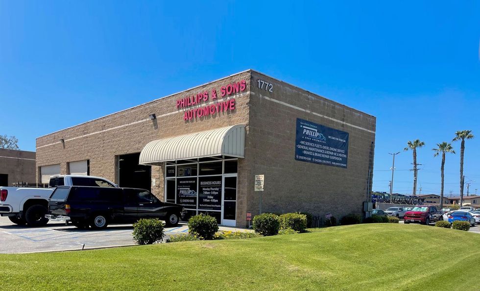 Exterior of a brick building; "Welding & Pipe Systems" sign. Vehicles parked nearby; palm trees in the background.
