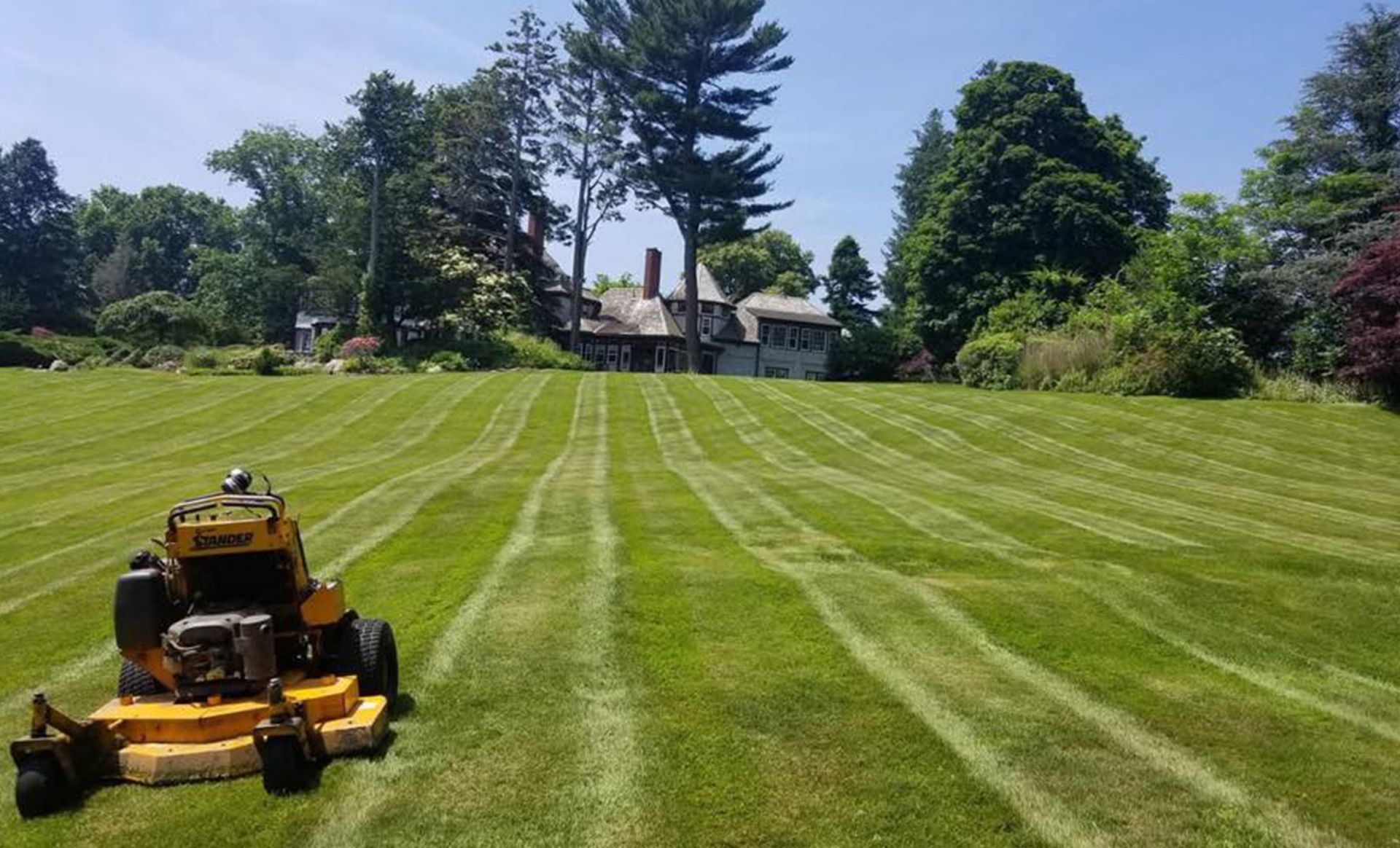 A yellow lawn mower is cutting a lush green lawn.