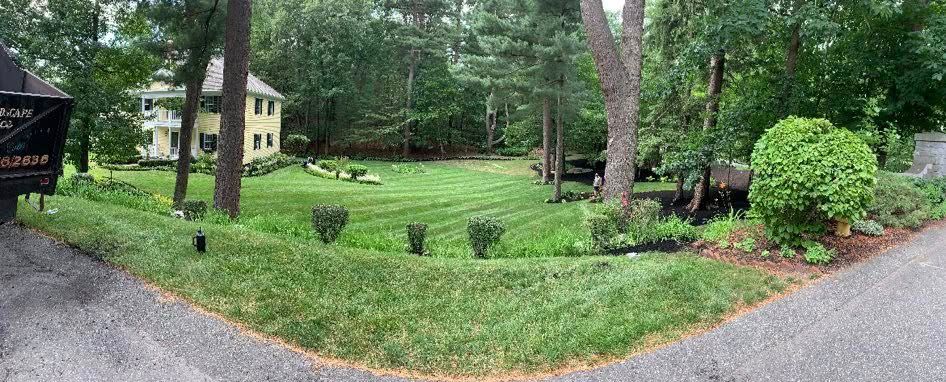 A large house is sitting in the middle of a lush green field surrounded by trees.