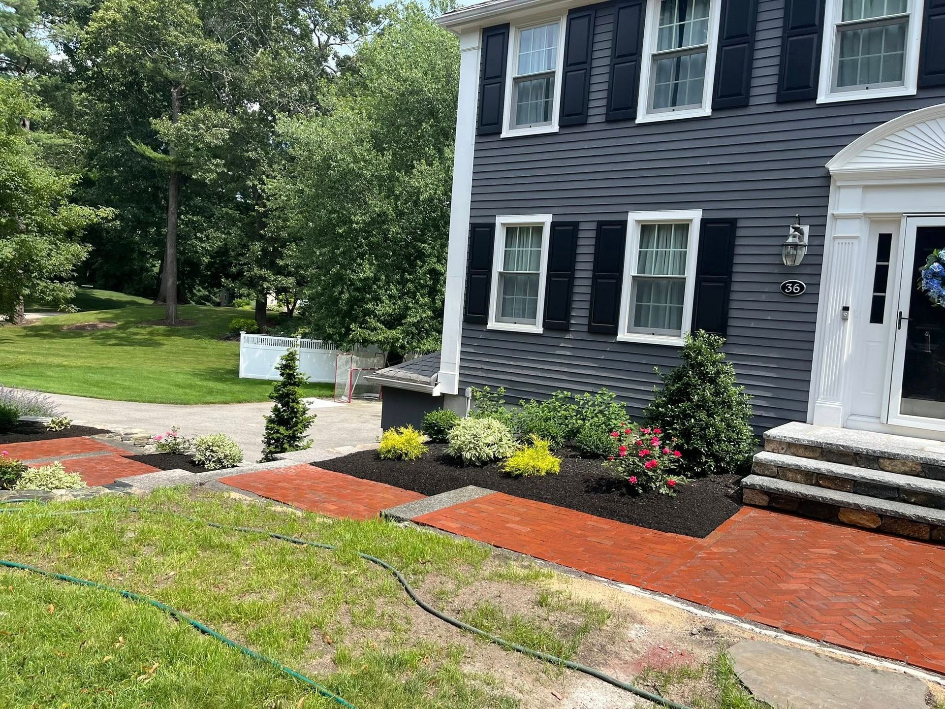 A large house with black shutters and a hose in front of it.