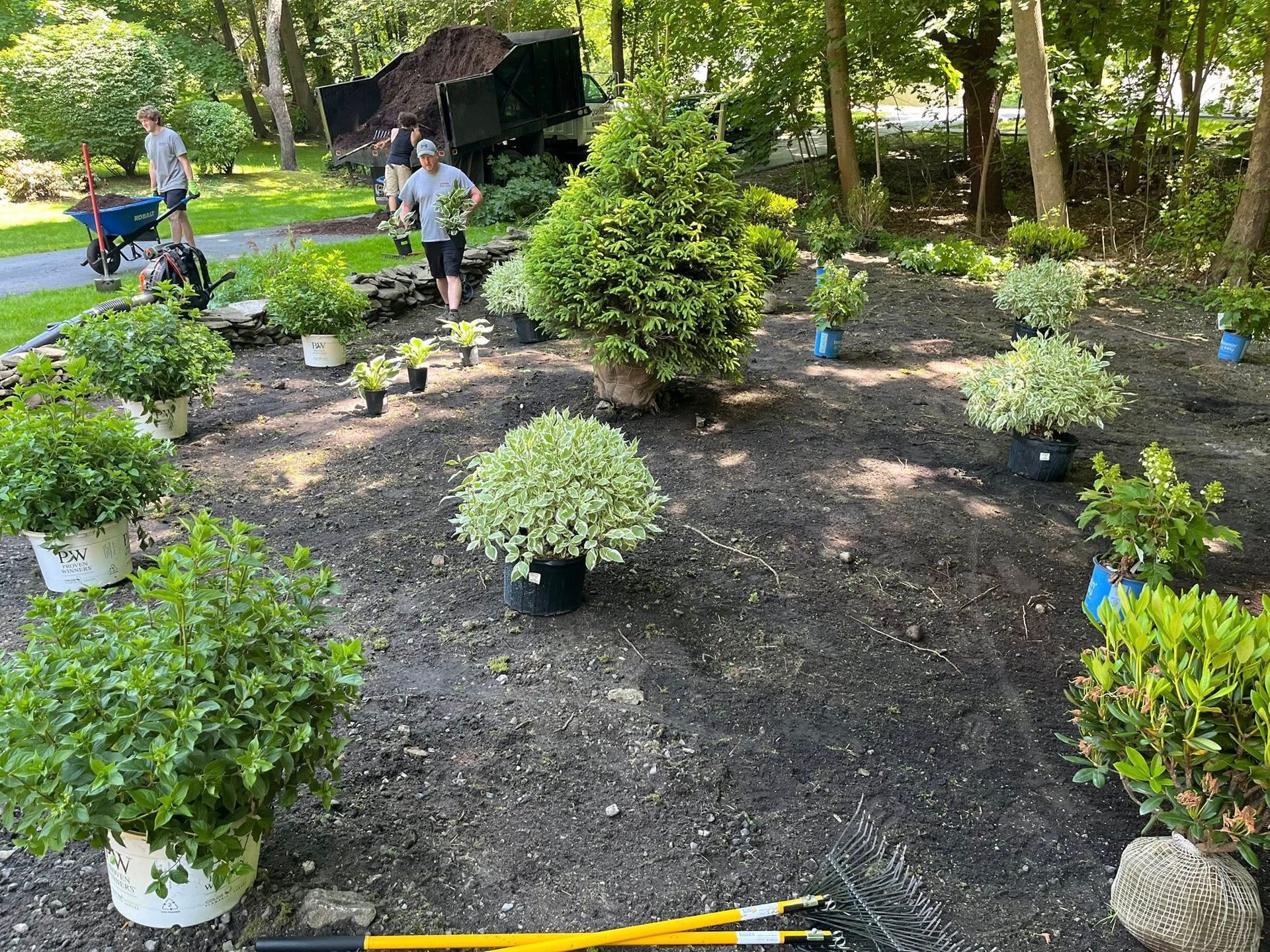 A group of people are working in a garden with lots of potted plants.