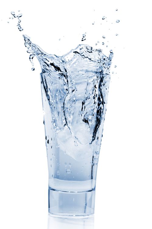 A clear glass filled with water splashing upward on a white background
