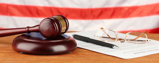 gavel, pen, eyeglasses and documents with USA flag in background
