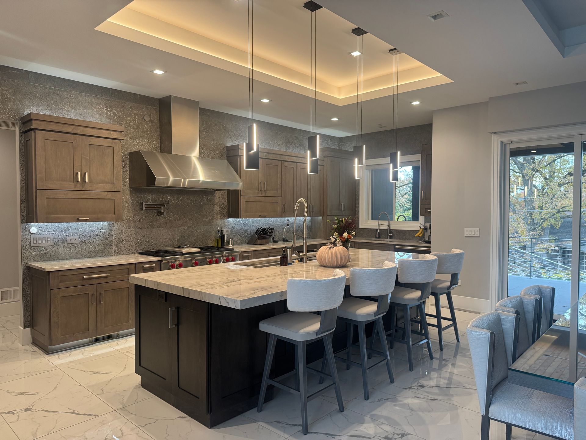Modern kitchen with large island, gray cabinets, pendant lights, and barstools by windows