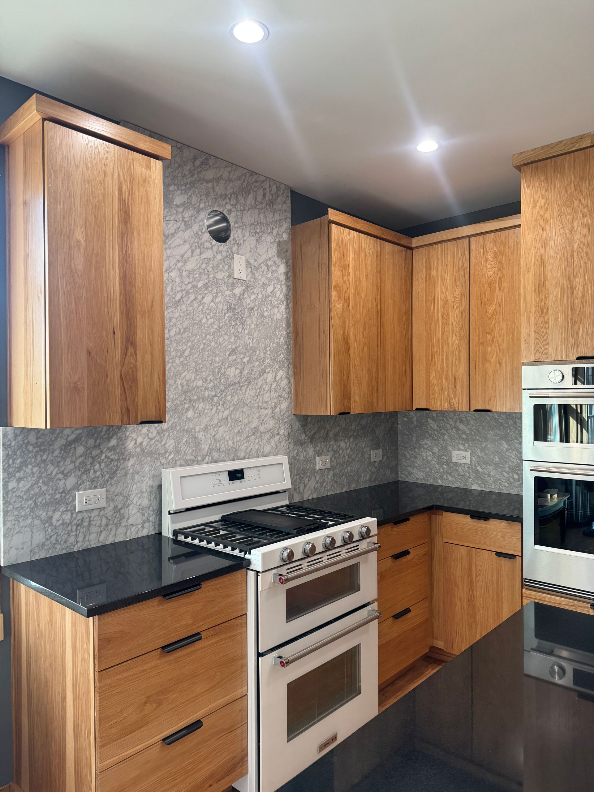 Compact kitchen with wood cabinets, dark countertops, and a stainless steel stove and oven.