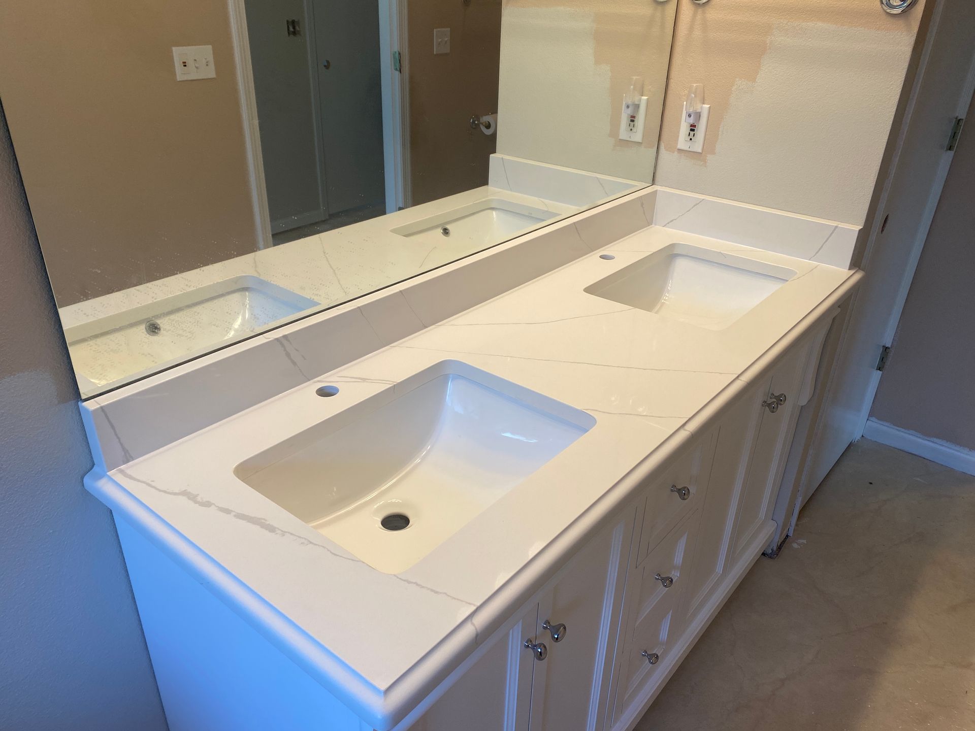 Double vanity bathroom counter with two white sinks and a large wall mirror