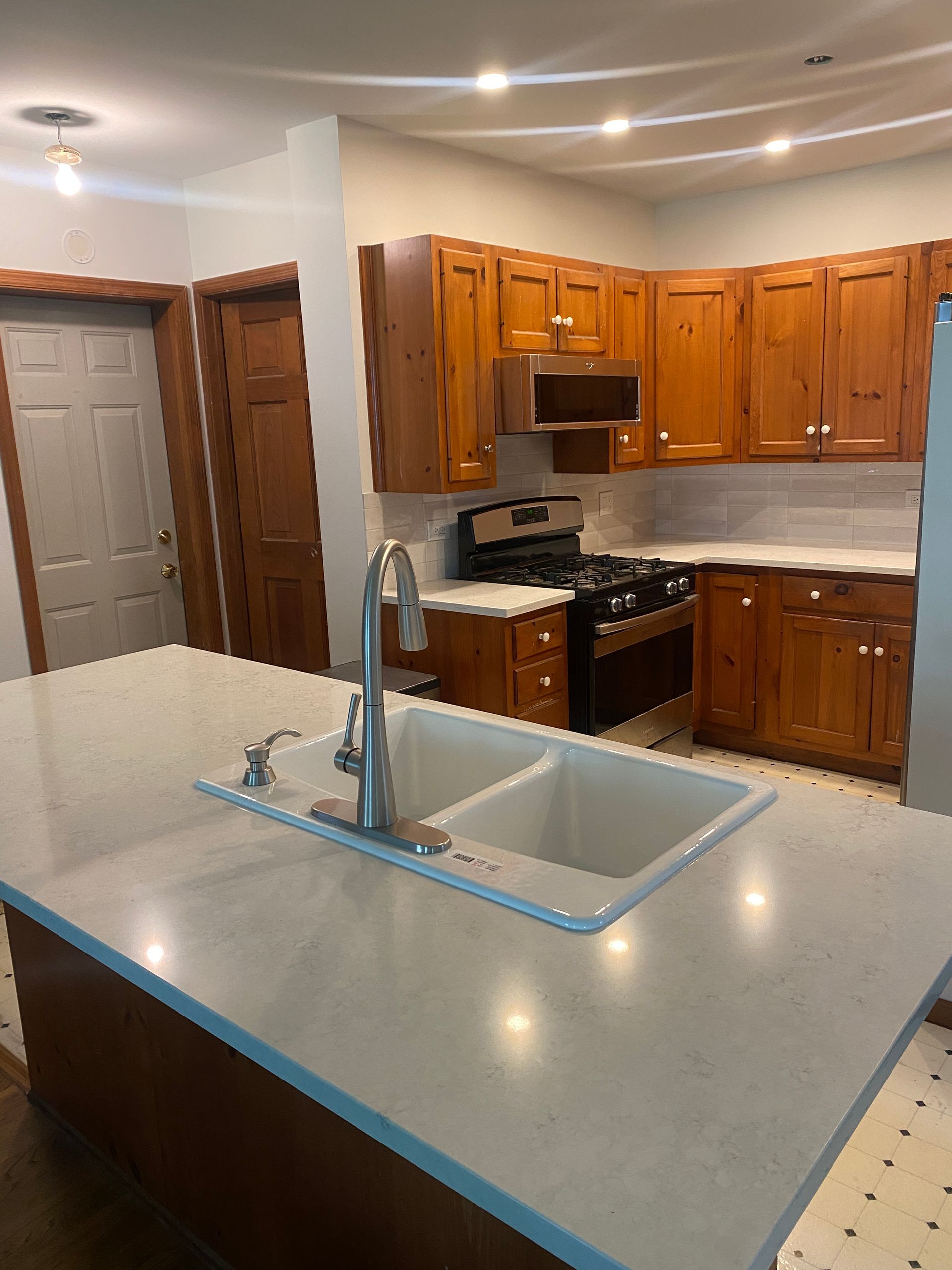 Modern kitchen with wooden cabinets, gray countertops, island sink, and stainless steel appliances