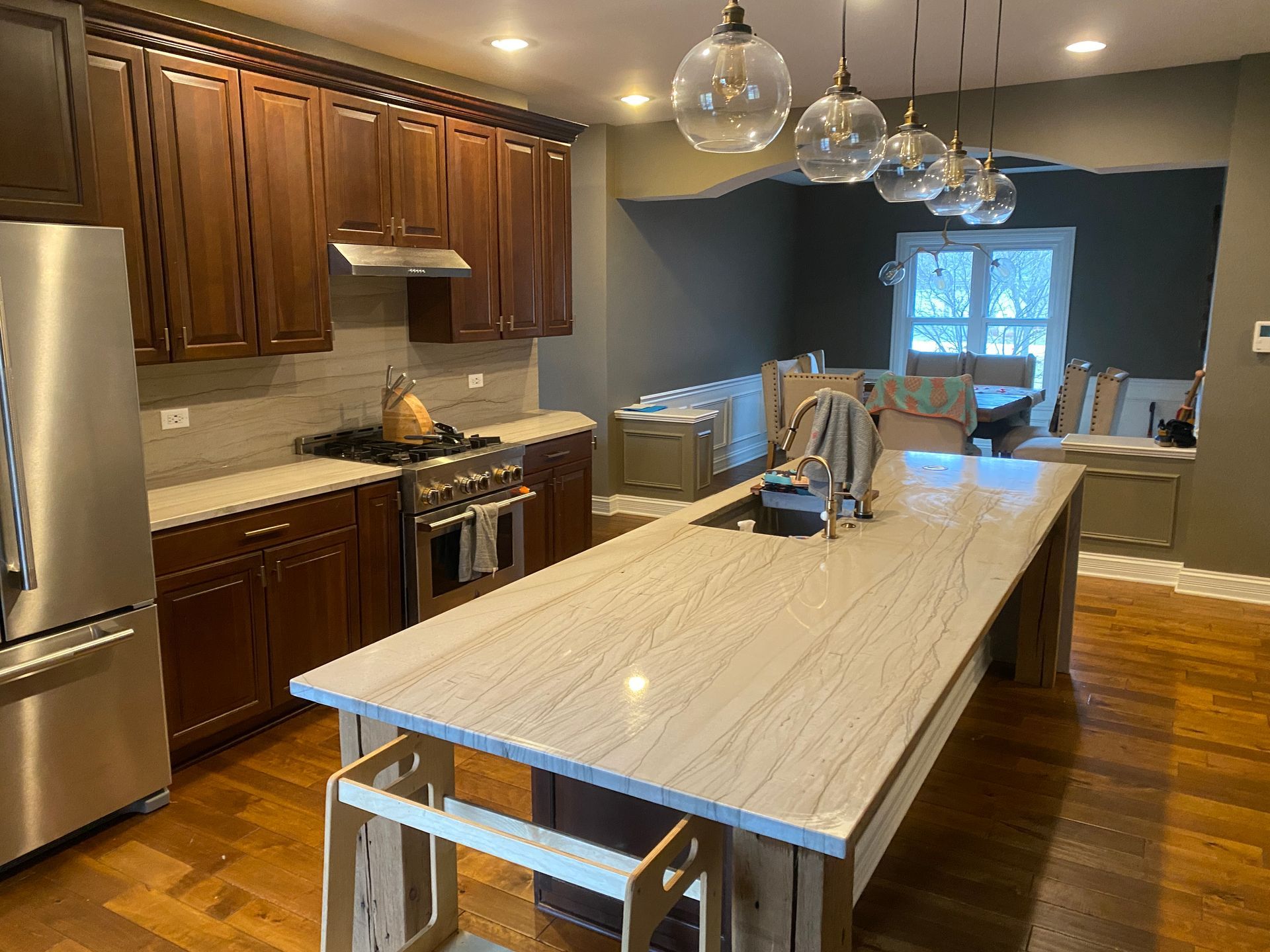 Modern kitchen with dark wood cabinets, long island, pendant lights, and hardwood floors