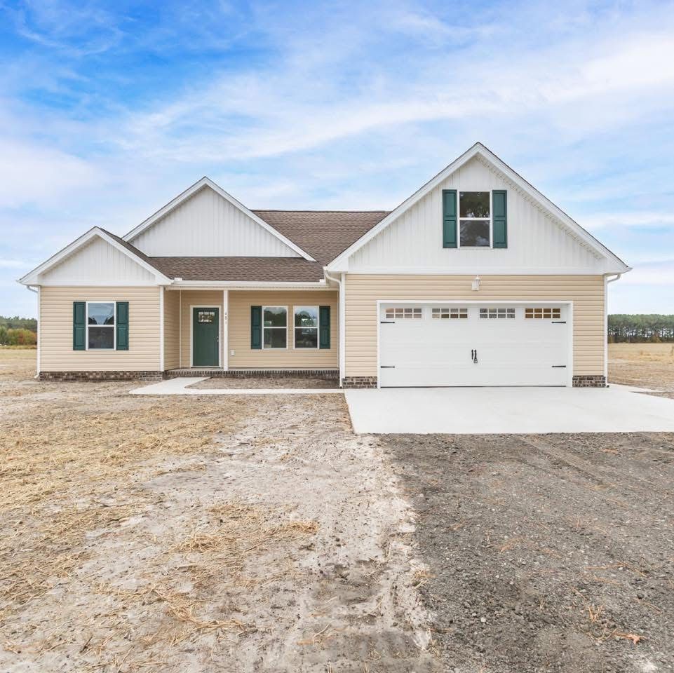 New beige single-story house with white trim, front porch, and two-car garage on a snowy lot