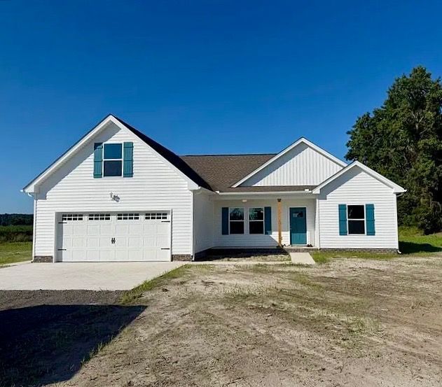 White suburban house with blue shutters, front garage, and gravel driveway under a clear blue sky