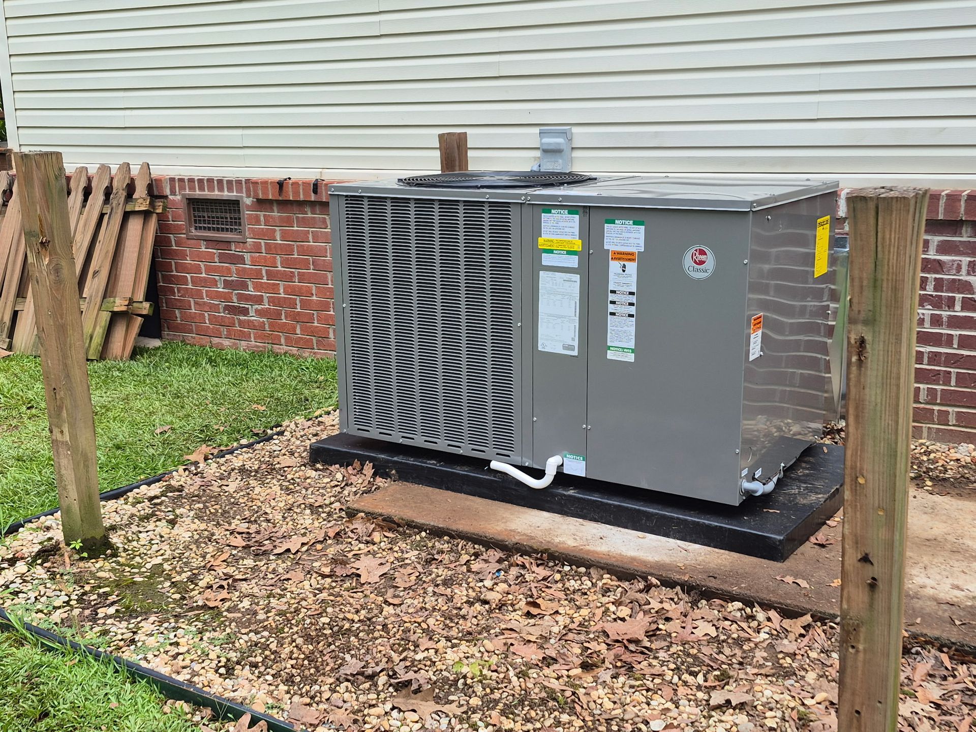 A large air conditioner is sitting in the backyard of a house.
