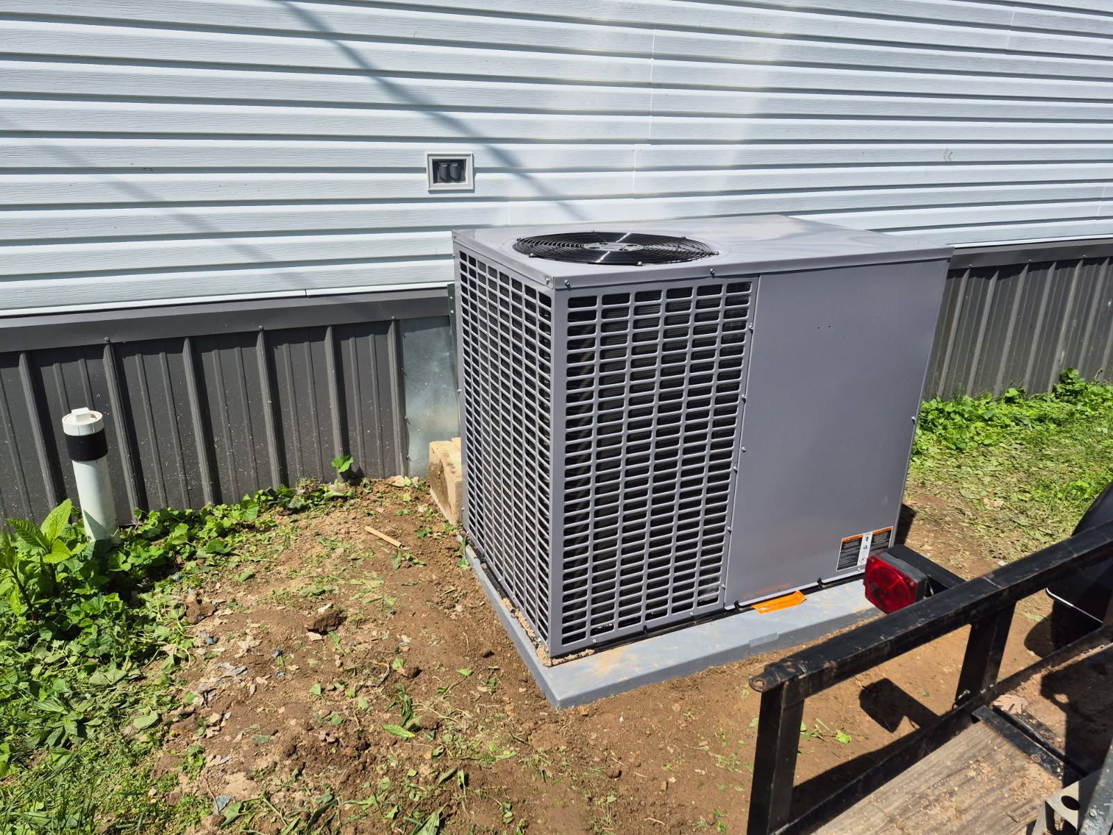 A large air conditioner is sitting outside of a house.