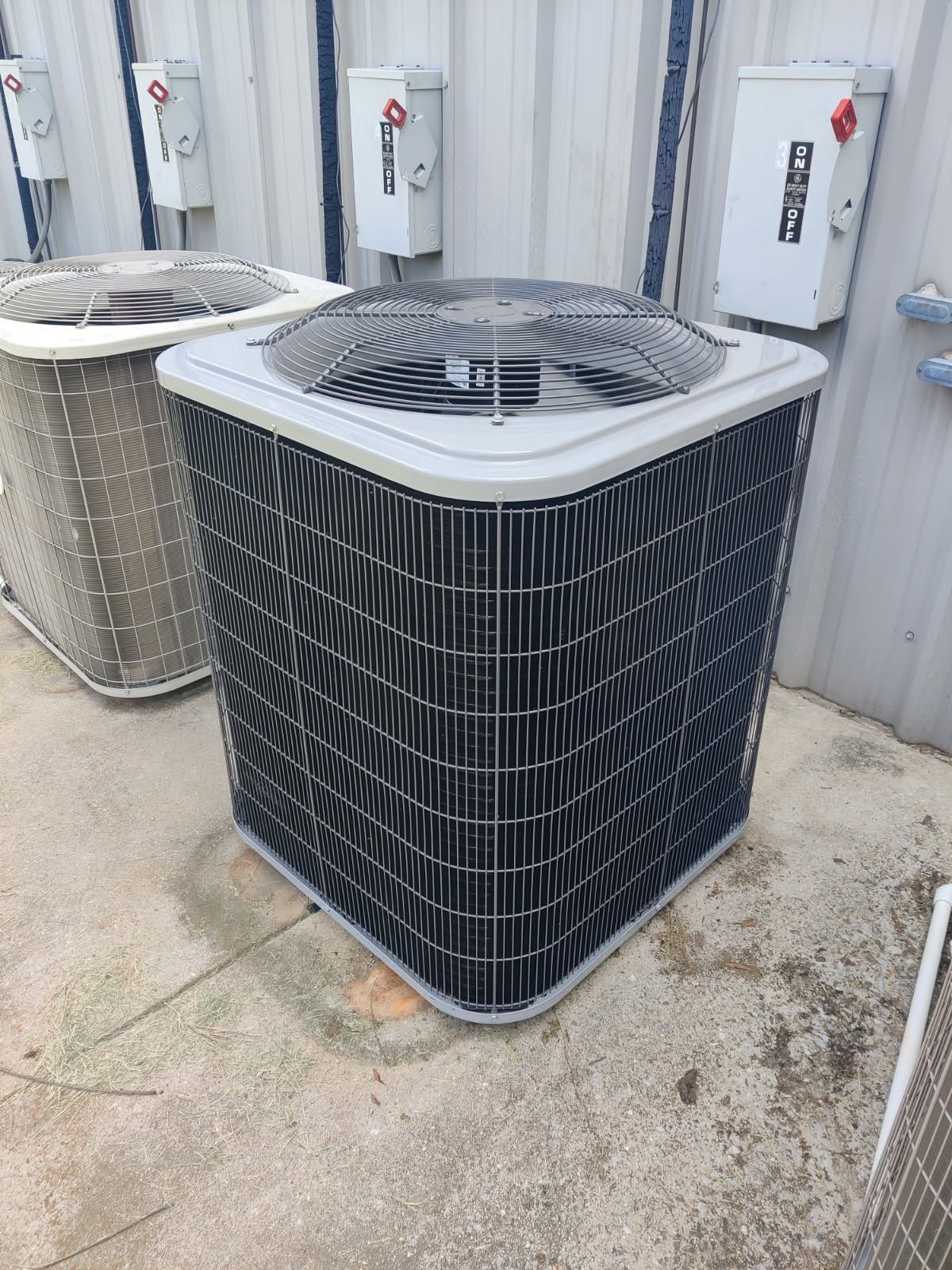 A large air conditioner is sitting on the ground in front of a building.