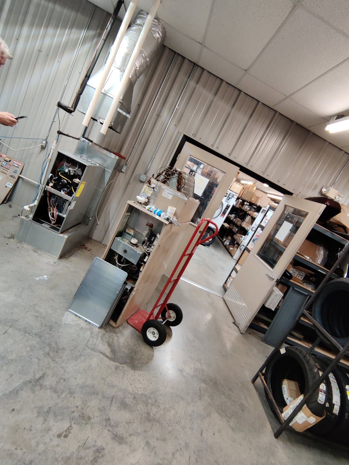 A man is standing in a room with a heater and a hand truck.