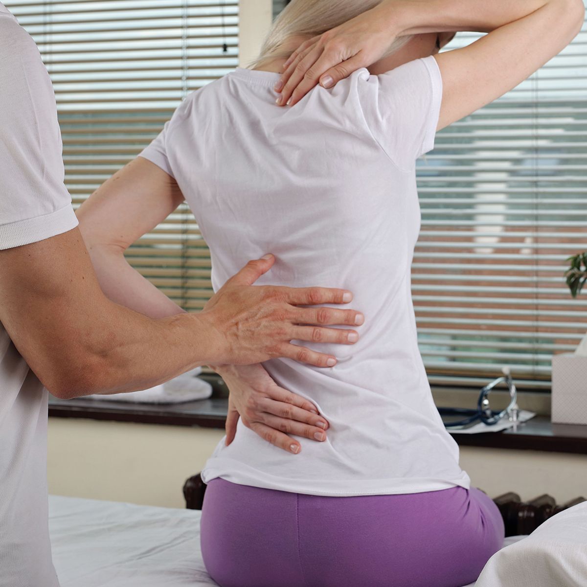 A woman in purple shorts is getting a massage from a man in a white shirt