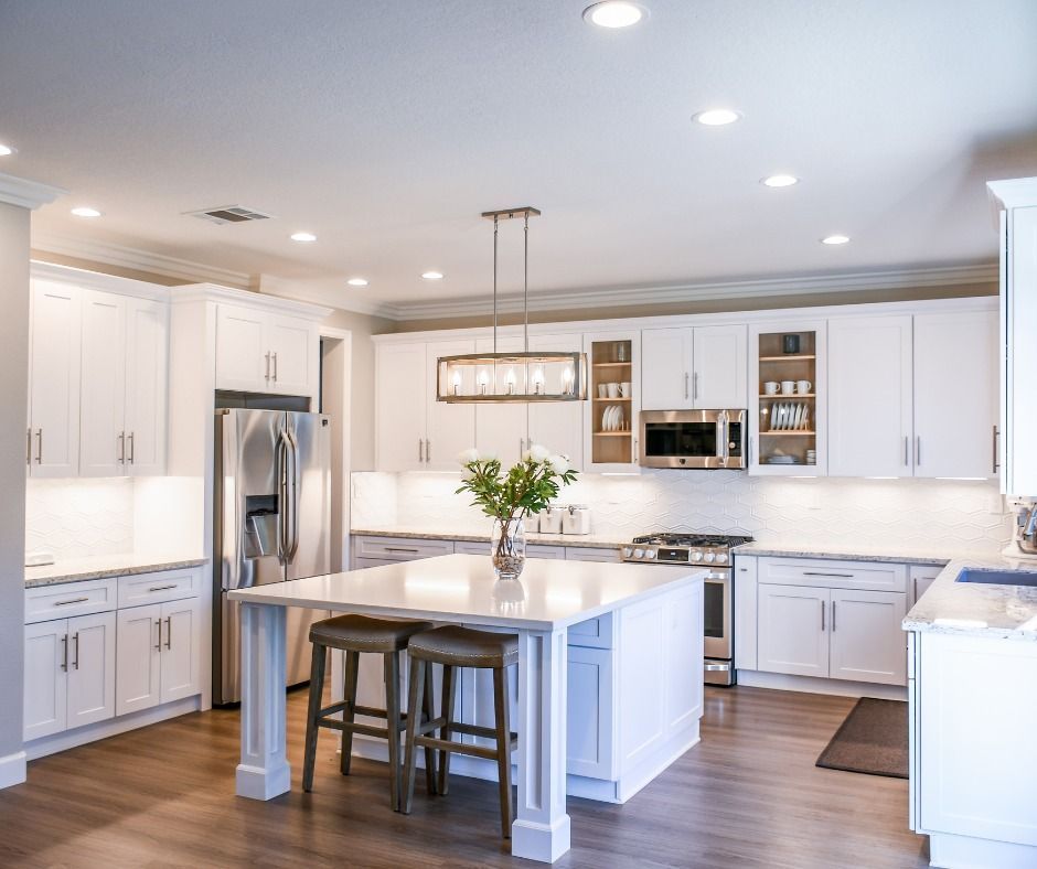 A kitchen with white cabinets, stainless steel appliances, and a large island.