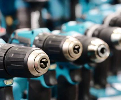 A bunch of drills are lined up in a row in a store.