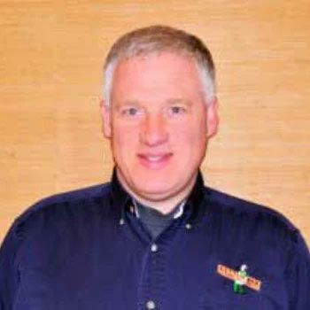 A man in a blue shirt is smiling for the camera.