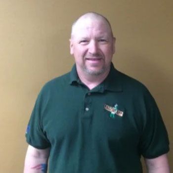 A man wearing a green polo shirt is smiling for the camera.