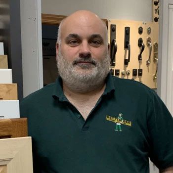 A man with a beard is standing in front of a display of door handles.