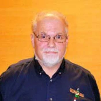 A man with a beard and glasses is wearing a blue shirt.