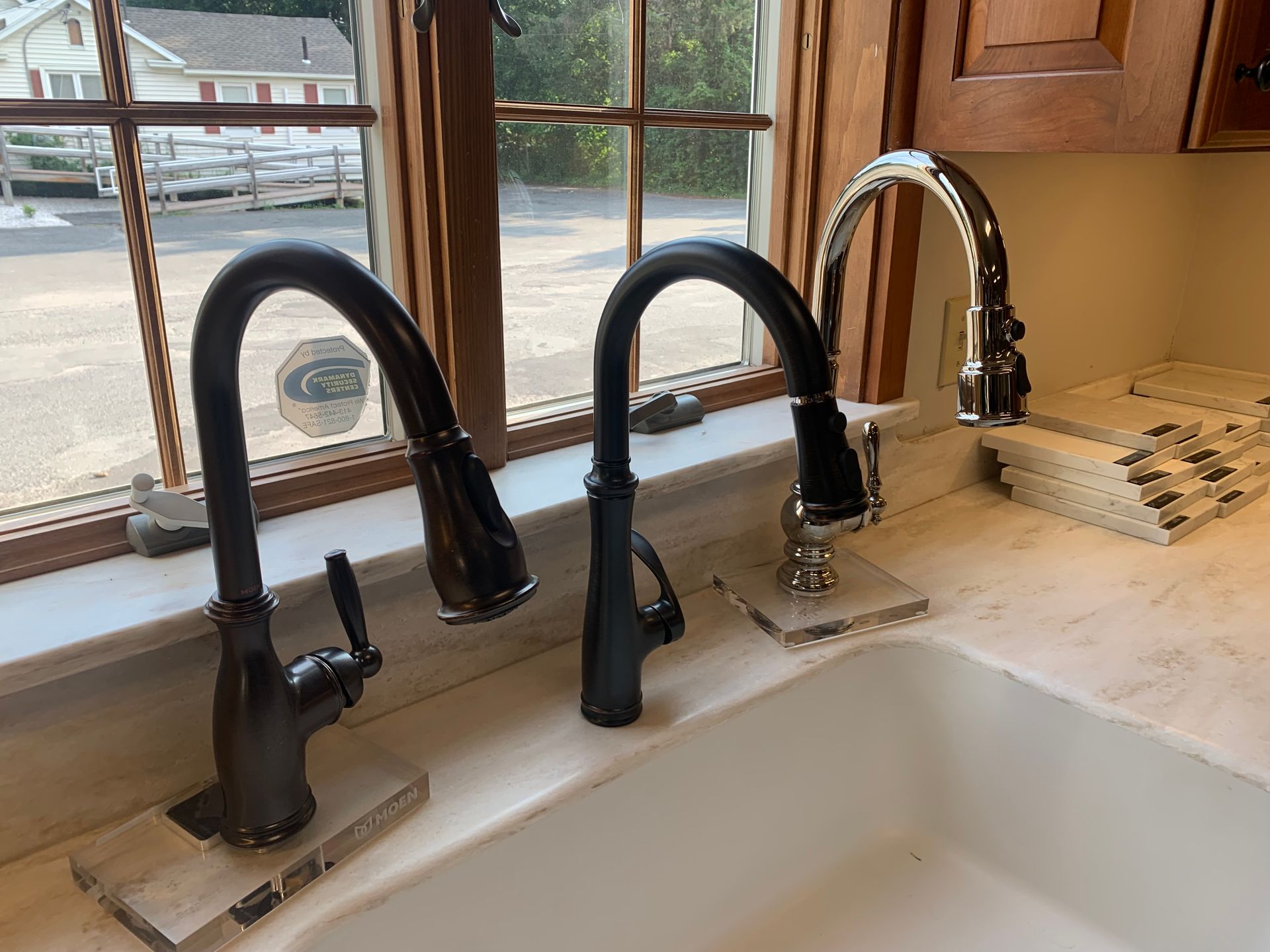 A kitchen sink with two black faucets next to a window
