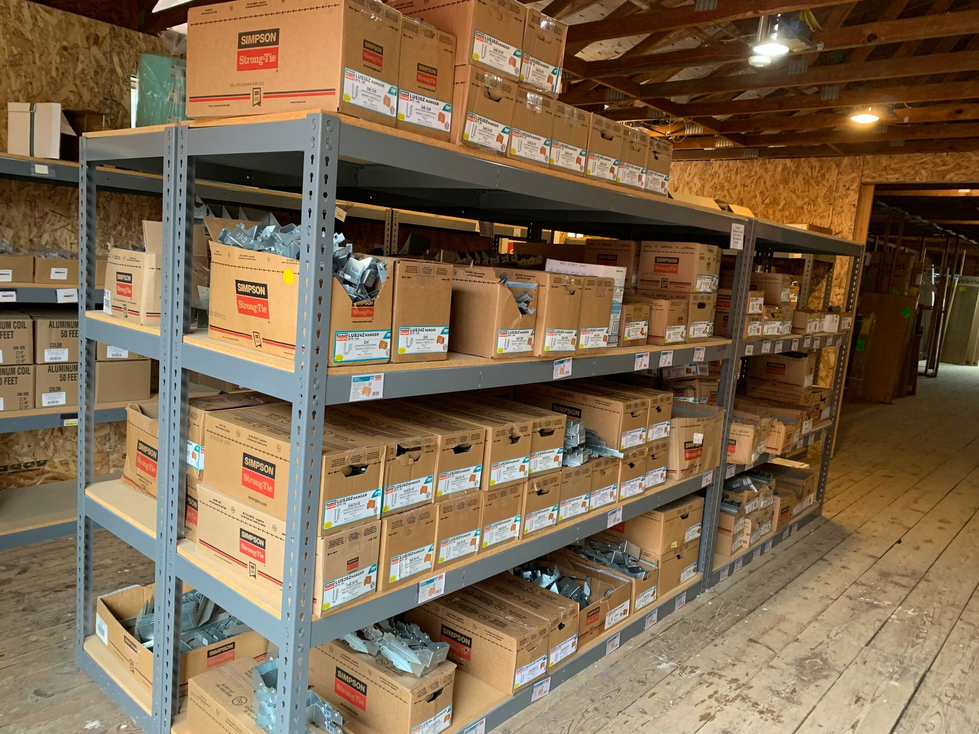 Shelves stocked with cardboard boxes of various sizes in a storage room. The shelves are metal and the boxes are brown.