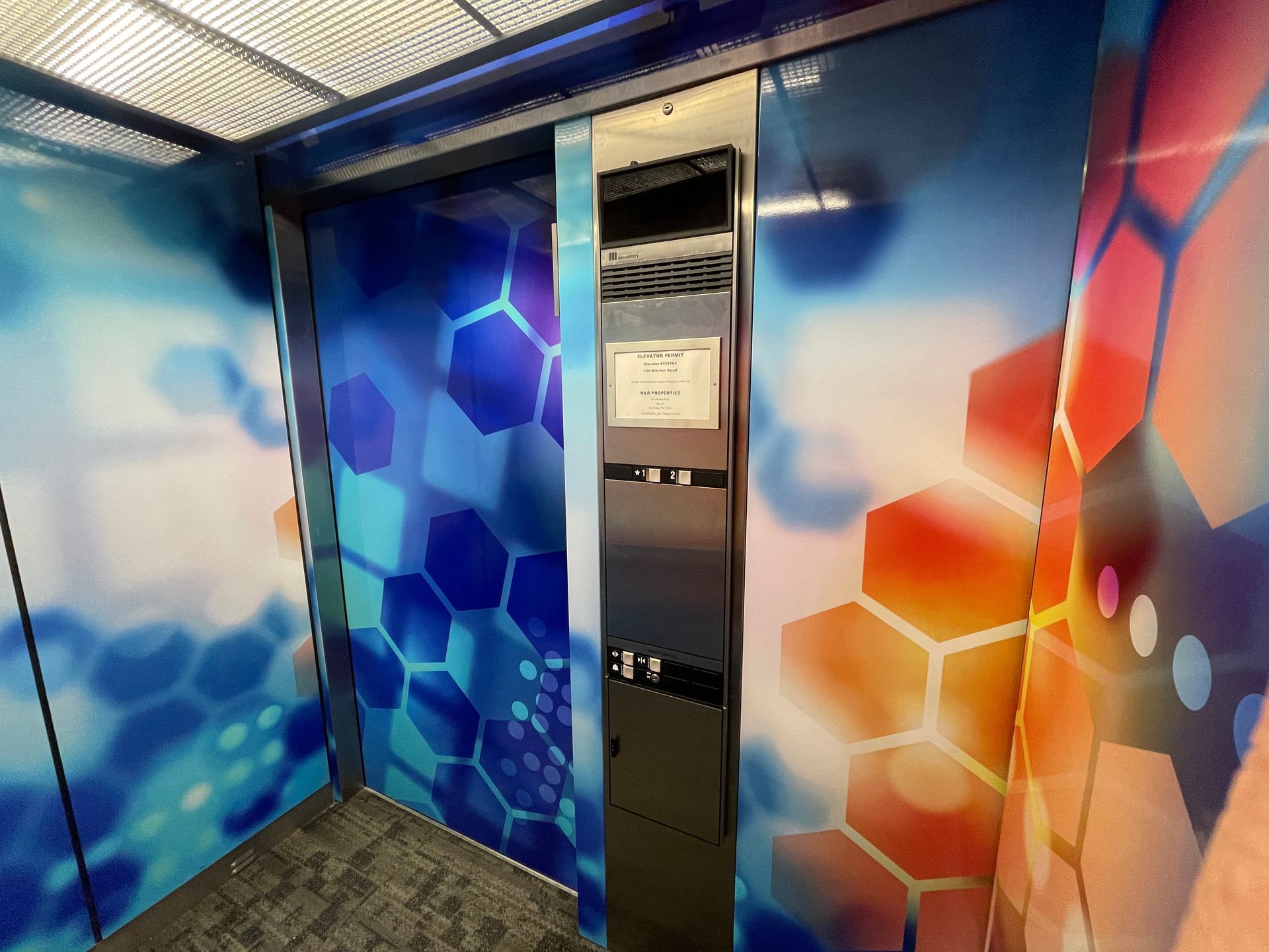 Reception desk with orange Avant logo and geometric blue wall design. Green wall background.