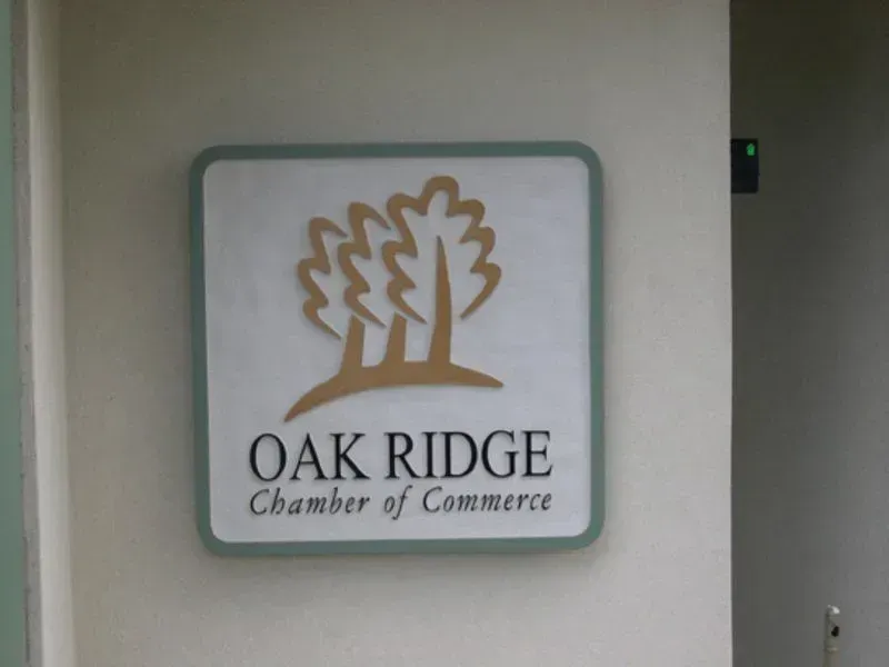 Sign for Oak Ridge Chamber of Commerce, featuring trees logo and text on a white and green square.